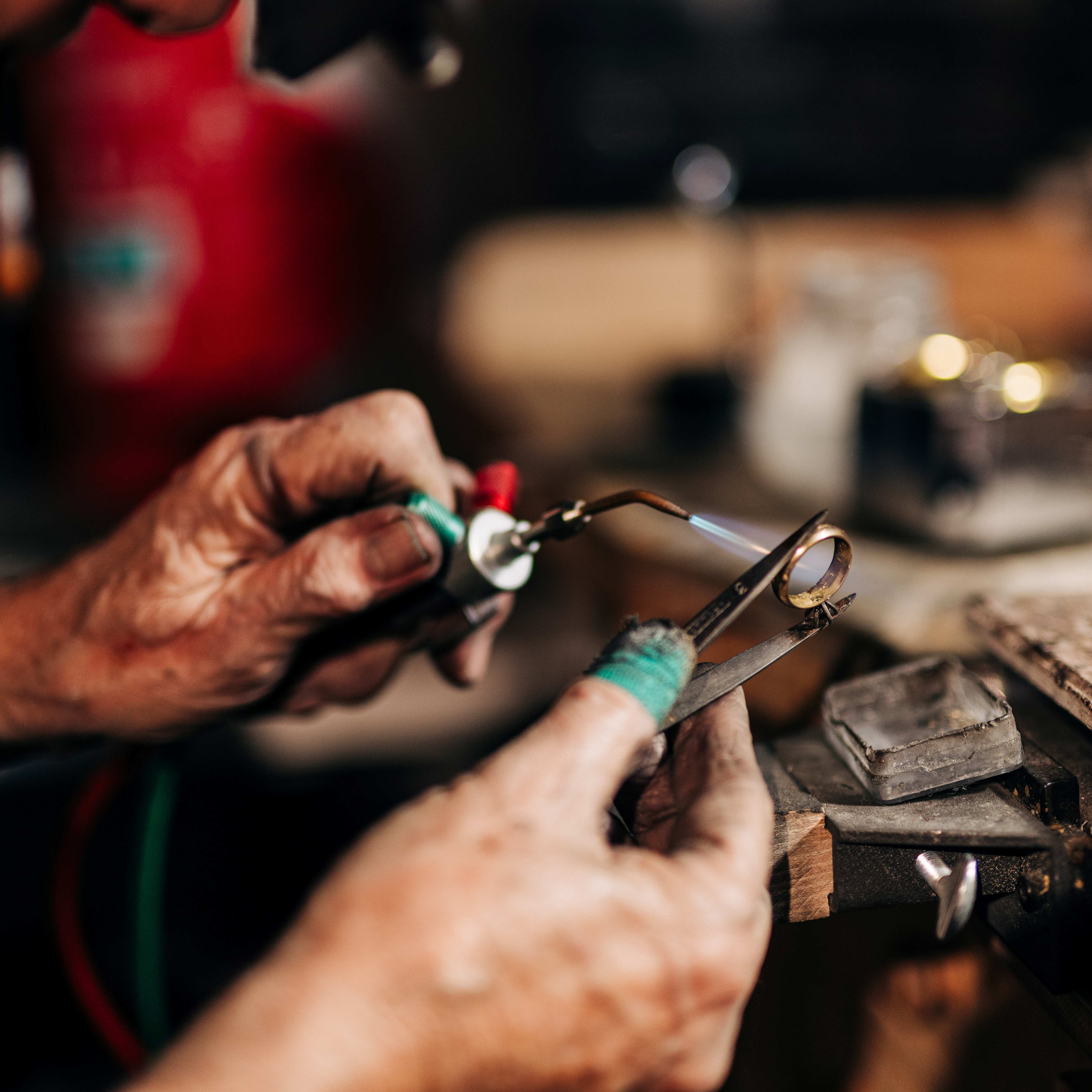 A goldsmith torch-soldering a gold ring at the jeweller's bench
